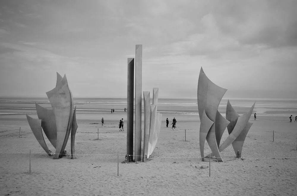 Sculpture Les Braves sur la plage d'Omaha Beach en Normandie, un mémorial rendant hommage au Débarquement, en noir et blanc.