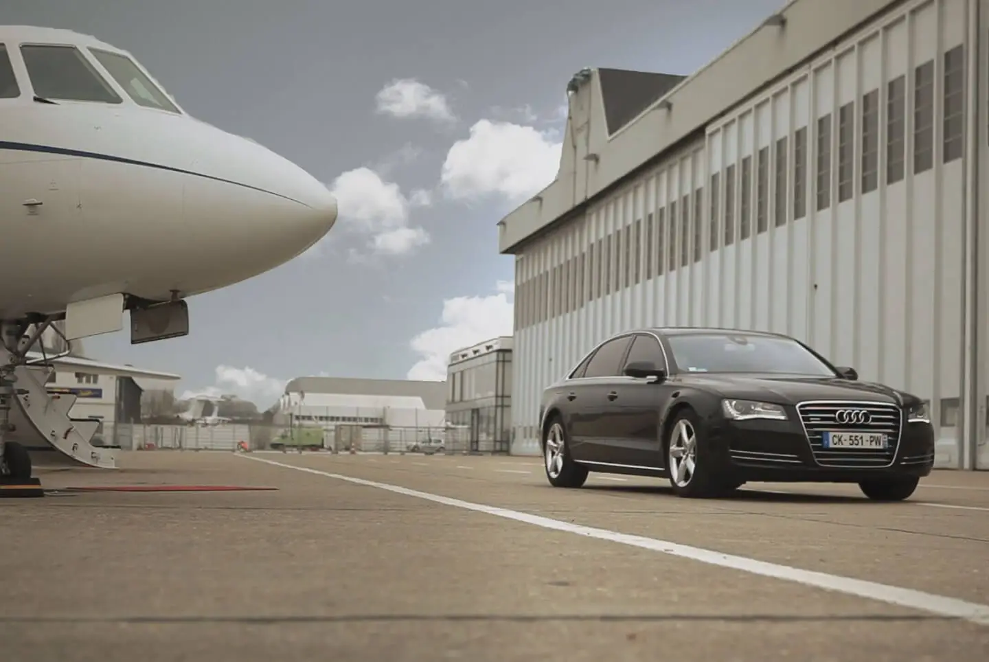 Voiture de luxe Service Prestige sur le tarmac de l'aéroport du Bourget à côté d'un jet privé, symbolisant l'accueil VIP et les transferts aéroport.