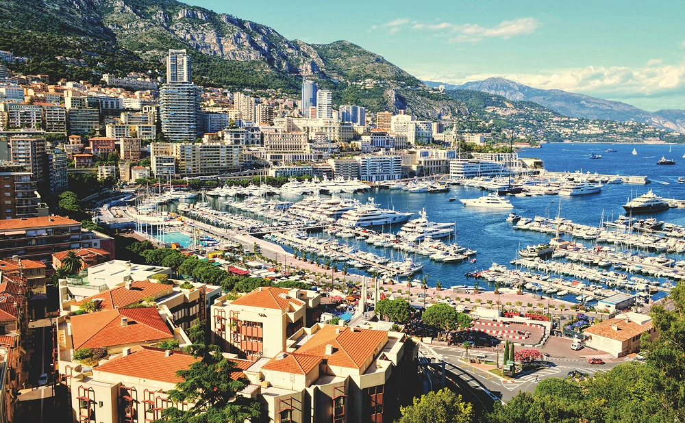 Vue aérienne panoramique de Monaco avec le port rempli de yachts de luxe et les immeubles modernes s'élevant sur les collines.